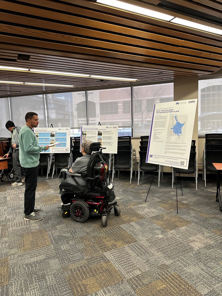 People talking and looking at poster boards during a transit plan open house.